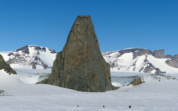 Storsponen i Hochlinfjella, finslipt av isen til en spiss nunatakk, består av smeltebergarten monzonitt. I nedre kant tre snøskutere på vei til fjellet. (Foto: Ane K. Engvik) Storsponen i Hochlinfjella, finslipt av isen til en spiss nunatakk, består av smeltebergarten monzonitt. I nedre kant tre snøskutere på vei til fjellet. (Foto: Ane K. Engvik)