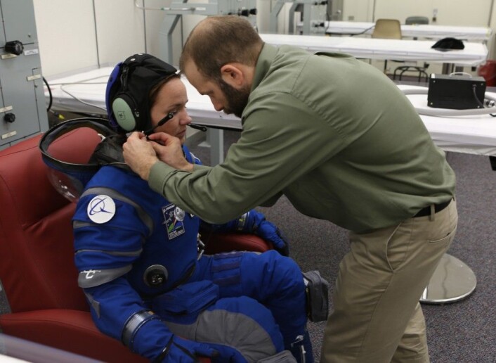 En tekniker fester kommunikasjonsenheten på en av de nye romdraktene før den settes under trykk inne i mannskapskvarterene på NASA Kennedy Space Center i Florida. (Foto: NASA/Cory Huston) En tekniker fester kommunikasjonsenheten på en av de nye romdraktene før den settes under trykk inne i mannskapskvarterene på NASA Kennedy Space Center i Florida. (Foto: NASA/Cory Huston)