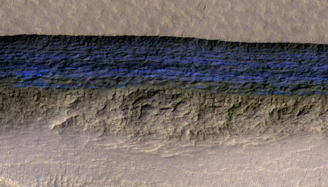Bildet viser et rundt 500 meter langt stykke av en av skrentene som ble undersøkt. Fargene i lyset vitner om at den nesten 130 meter høye veggen består av frossent vann.  (Foto:  NASA/JPL-Caltech/UA/USGS)