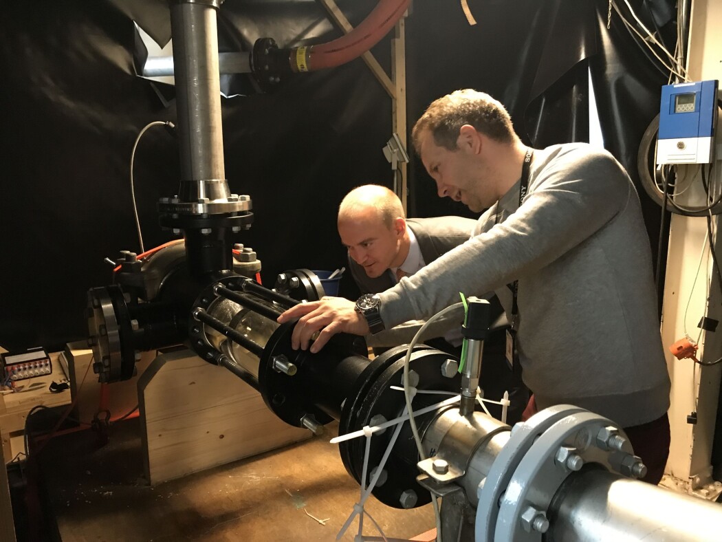 Samuel Bockenhauer (til venstre) fra det amerikanske energidepartement (US DoE) viste stor interesse på omvisningen i Vannkraftlaboratoriet ved NTNU. Her er det PhD Erik Volent (til høyre) som forklarer hvordan utfordringer med erosjon kan løses med forskning på vannkraftventiler og dyser. (Foto: Juliet Landrø/HydroCen) Samuel Bockenhauer (til venstre) fra det amerikanske energidepartement (US DoE) viste stor interesse på omvisningen i Vannkraftlaboratoriet ved NTNU. Her er det PhD Erik Volent (til høyre) som forklarer hvordan utfordringer med erosjon kan løses med forskning på vannkraftventiler og dyser. (Foto: Juliet Landrø/HydroCen)