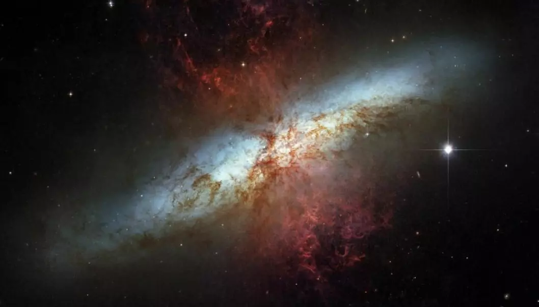 M82 er et eksempel på en veldig aktiv galakse der det dannes og eksploderer massevis av stjerner. Herfra sendes det ut galaktiske vinder av hydrogengass som er markert som røde områder på bildet.  (Foto: NASA/ESA)