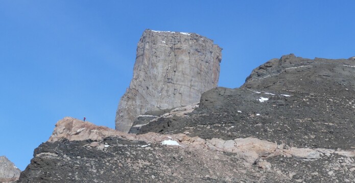 Geologene undersøker fjellklippen Stabben. Stabben har opphav som en intrusjon av den massive bergarten syenitt og ble stående igjen som en standhaftig klippe under senere tiders erosjon. Svart gabbro på fjellkammen foran blir kuttet av et rødt granittlag. (Foto: Ane K. Engvik) Geologene undersøker fjellklippen Stabben. Stabben har opphav som en intrusjon av den massive bergarten syenitt og ble stående igjen som en standhaftig klippe under senere tiders erosjon. Svart gabbro på fjellkammen foran blir kuttet av et rødt granittlag. (Foto: Ane K. Engvik)