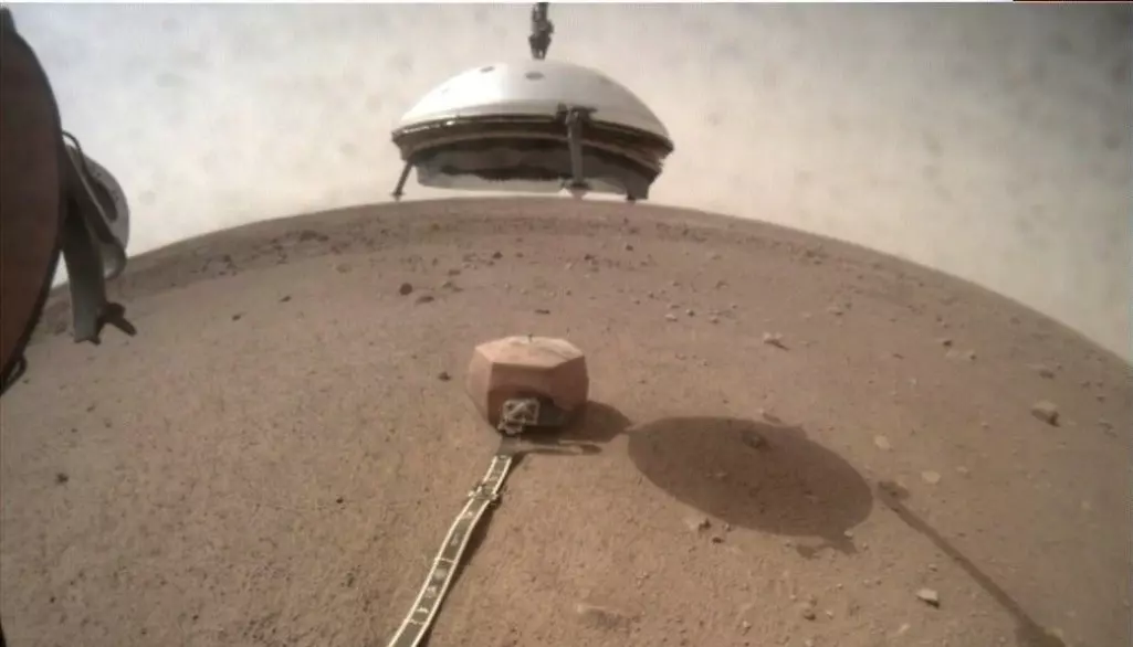Her er InSight på Mars. Den bruker robot-armen til å heise ned et skjold over jordskjelv-måleren. (Foto: NASA/JPL-Caltech)