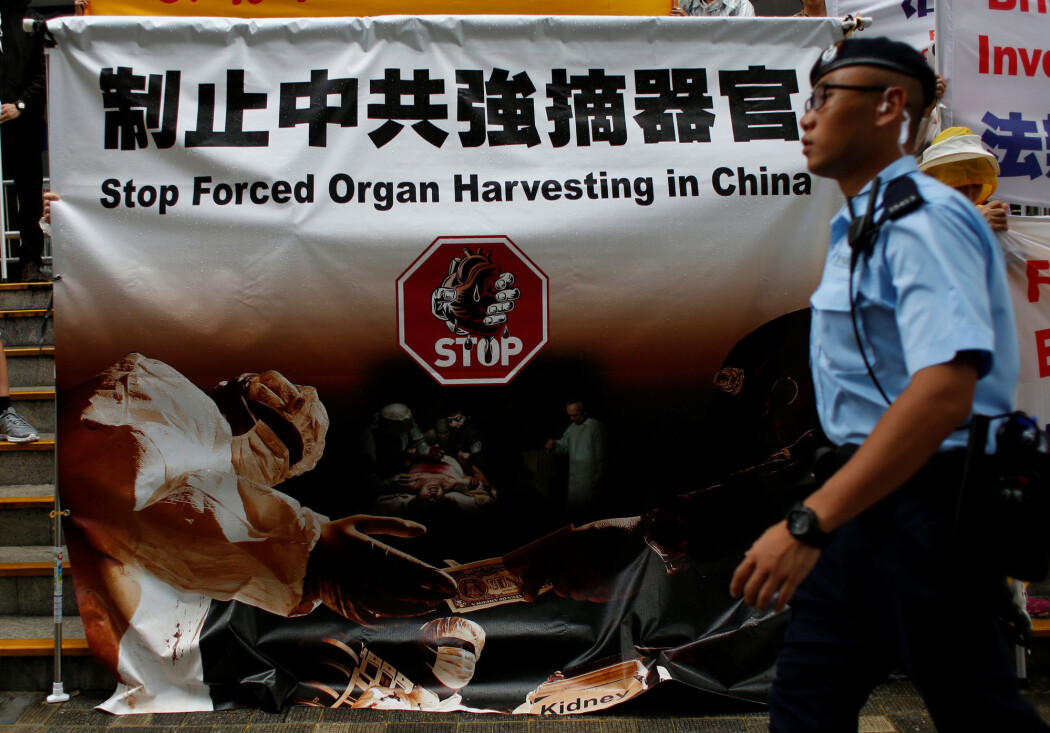 Hong Kong, 2016: En politimann går forbi en plakat som protesterer mot bruk av organer fra henrettede Falun Gong-medlemmer. (Foto: Bobby Yip, Reuters/NTB scanpix) Hong Kong, 2016: En politimann går forbi en plakat som protesterer mot bruk av organer fra henrettede Falun Gong-medlemmer. (Foto: Bobby Yip, Reuters/NTB scanpix)