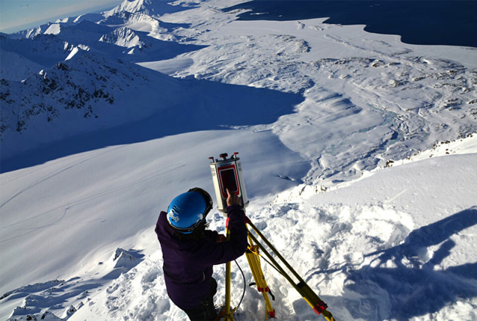 Alexander Prokop, skredforsker ved UNIS, bruker en terrestrisk laserskanner for å måle snødybde på Svalbard. (Foto: Privat)