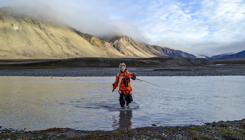 Forskar Pernilla Carlsson ved NIVA går i land frå Ebbaelva ved Petuniabukta, Svalbard, med ein prøvetakar for miljøgifter i handa. (Foto: Sverre Johansen)