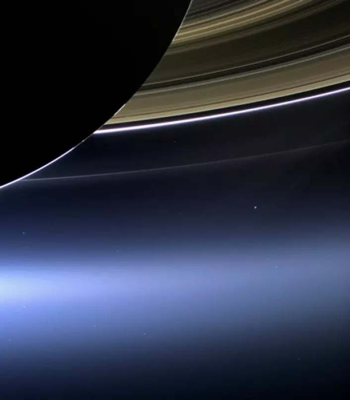 Saturn, dens ringer, og jorda (blått punkt nede til høyre) sett av romsonden Cassini. (Foto: NASA)