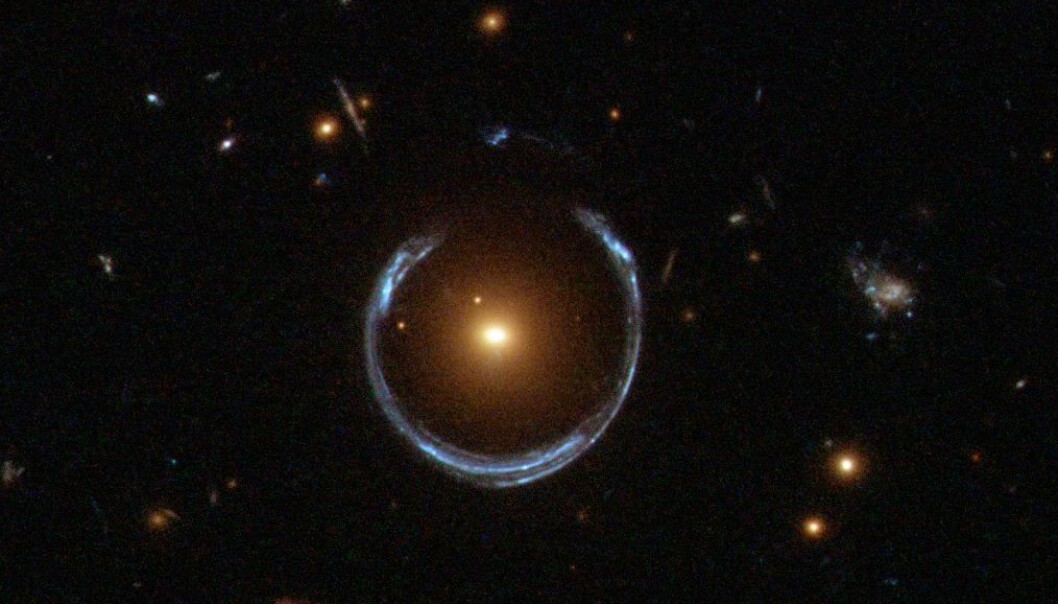 Dette er ikke en ring rundt en stjerne, selv om det ser sånn ut. Lyset fra en blålig galakse har blitt fordreid av en svært massiv, rød galakse i midten. Gravitasjonen gjør at lyset blir tøyd ut i tyngdefeltet. (Bilde: ESA/Hubble/NASA) Dette er ikke en ring rundt en stjerne, selv om det ser sånn ut. Lyset fra en blålig galakse har blitt fordreid av en svært massiv, rød galakse i midten. Gravitasjonen gjør at lyset blir tøyd ut i tyngdefeltet. (Bilde: ESA/Hubble/NASA)