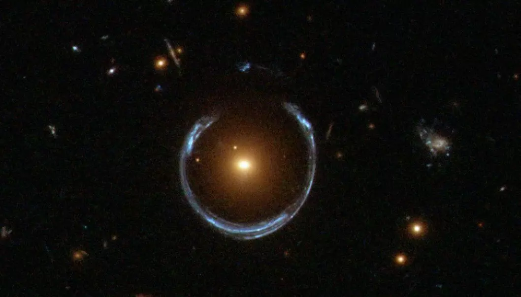 Dette er ikke en ring rundt en stjerne, selv om det ser sånn ut. Lyset fra en blålig galakse har blitt fordreid av en svært massiv, rød galakse i midten. Gravitasjonen gjør at lyset blir tøyd ut i tyngdefeltet. (Bilde: ESA/Hubble/NASA)