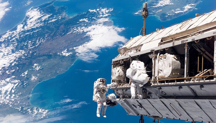 Astronauter jobber på utsiden av romstasjonen - New Zealand kan sees i bakgrunnen. (Bilde:NASA) Astronauter jobber på utsiden av romstasjonen - New Zealand kan sees i bakgrunnen. (Bilde:NASA)