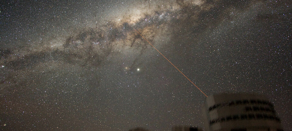 Dette er Melkeveien i all sin prakt, slik vi ser den fra jorden. Er det noen der ute som prøver å få tak i oss? Dette er ESOs VLT-teleskop, og dette er bare et illustrasjonsbilde. Laserstrålen kommer fra teleskopet, bare så det er gjort klart. (Illustrasjonsbilde: Y.Beletsky/ESO/CC BY 3.0)