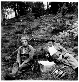 En svensk og en norsk grenseboer har møttes like etter krigen for sammen å tå seg en tår i det fri. Bildet er tatt i Vassbotten, lengst sør i Østfold. (Foto: Bohusläns museum) En svensk og en norsk grenseboer har møttes like etter krigen for sammen å tå seg en tår i det fri. Bildet er tatt i Vassbotten, lengst sør i Østfold. (Foto: Bohusläns museum)