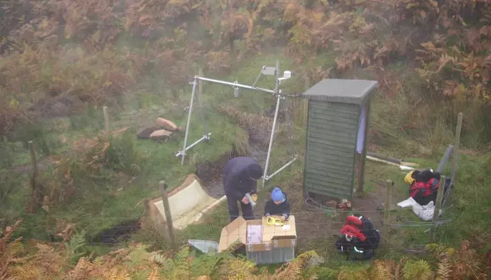 NIVA-forsker Benoît Demars på feltarbeid ved ei renne i bekken sammen med sønnen sin en typisk tåkete dag i Nordøst-Skottland. Det er lav vannføring i bekken, og derfor er vannet i renna klart. (Foto: Privat).