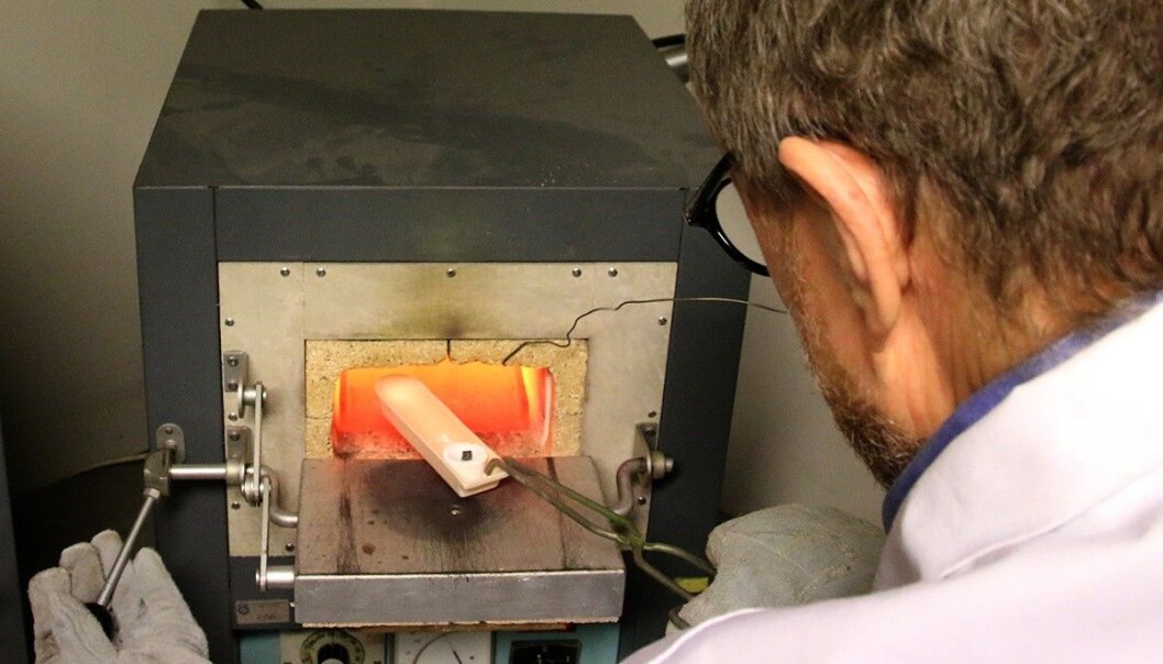 Overingeniør Pål Ulseth setter en kapell inn i den 900 grader varme ovnen. (Foto: Idun Haugan, NTNU) Overingeniør Pål Ulseth setter en kapell inn i den 900 grader varme ovnen. (Foto: Idun Haugan, NTNU)