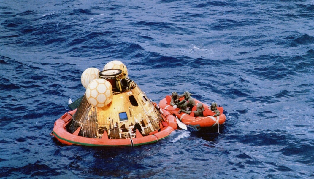 Astronautene venter på å bli plukket opp i helikopter. De har tatt på seg isolasjonsdrakter som skal hindre eventuell månesmitte. (Foto: NASA) Astronautene venter på å bli plukket opp i helikopter. De har tatt på seg isolasjonsdrakter som skal hindre eventuell månesmitte. (Foto: NASA)