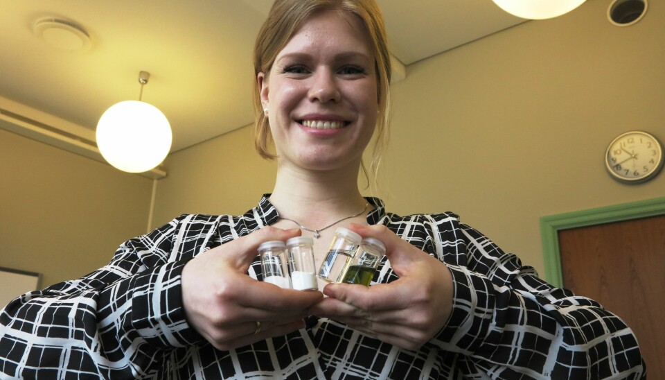 Kristine Opsvik Wikene holder fire prøveglass som inneholder (fra venstre) sukrose, glukose, den flytende blandingen av de to stoffene og NADES-blandingen med lysfølsomt fargestoff.  (Foto: Bjarne Røsjø, UiO)