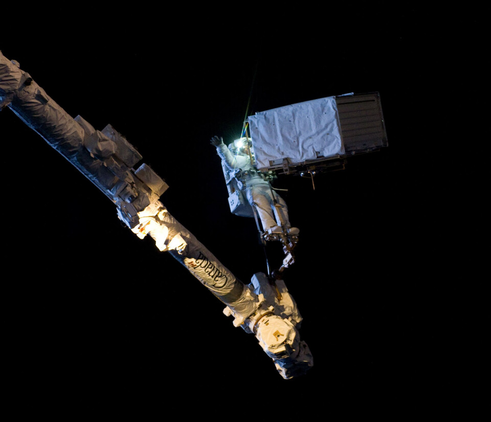 Alexander Gerst, ESAs tyske astronaut, holder en pumpe på 380 kilo på strak arm mens han står på robotarmen Canadarm under en romvandring på den internasjonale romstasjonen i 2014. (Foto: ESA/NASA)