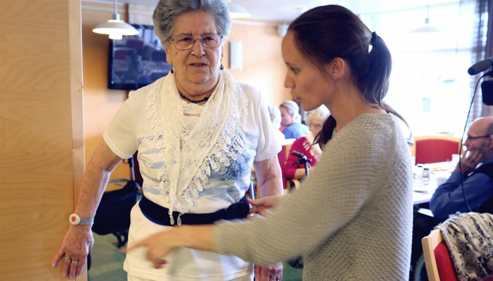 Skjoldvor Måsøval, resident at the Laugsand day care centre, is helped by a scientist to adjust the belt that will trigger an alarm if she is unlucky and falls. (Photo: Kjersti Fikse Ness, Adresseavisen)
