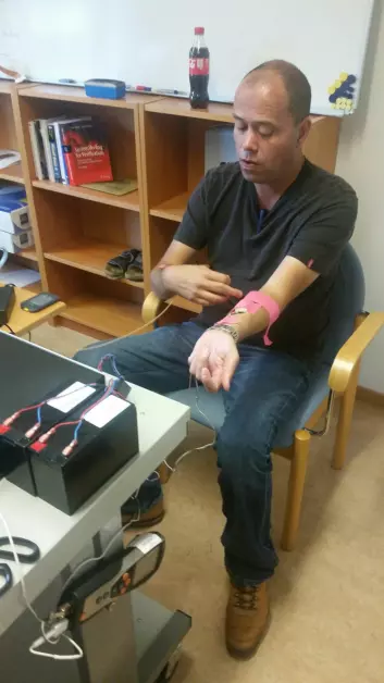 Bjarte Ellingsen, oppfinnerens sønn, prøver en prototype av mikrovibratoren som måler blodsukkeret på armen.  (Foto: Olav Ellingsen)