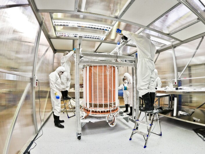 Her holder teknikerne på å legge siste hånd på detektoren, som nå er plassert i vanntanken. Detektoren rommer 3,3 tonn flytende xenon ved om lag 100 minusgrader. I tanken er detektoren plassert i en «termos» av rustfritt stål. (Foto: The Xenon Collaboration) Her holder teknikerne på å legge siste hånd på detektoren, som nå er plassert i vanntanken. Detektoren rommer 3,3 tonn flytende xenon ved om lag 100 minusgrader. I tanken er detektoren plassert i en «termos» av rustfritt stål. (Foto: The Xenon Collaboration)
