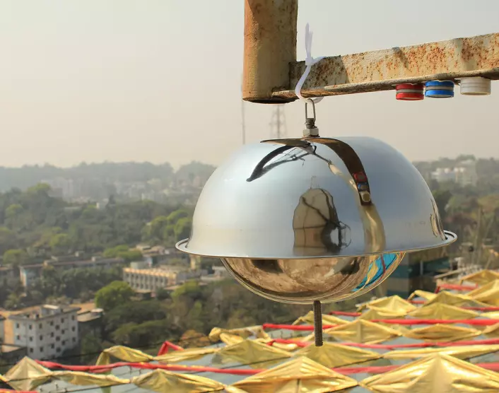 Bildet viser luftmålere inne i byen Chittagong i Bangladesh. Den store «metalldomen» samler inn luftprøver for analyse av miljøgifter, mens de tre små sylindrene måler nitrogendioksid (blå), svoveldioksid (rød) og ozon (hvit).  (Foto: Scott Randall/NILU)