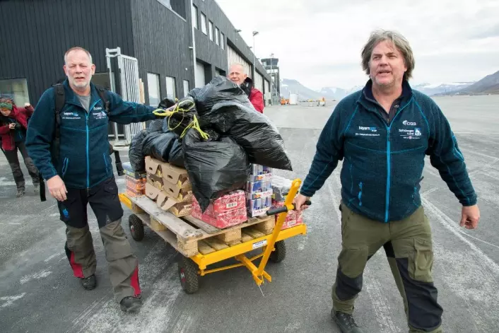 Øyvind Enger (f.v.), Stig Larsen og Jørn Hurum sørger for at avsindige mengder med Coca Cola og energidrikker står klar til helikoptertransporten fra flyplassen i Longyearbyen.  (Foto: Yngve Vogt)