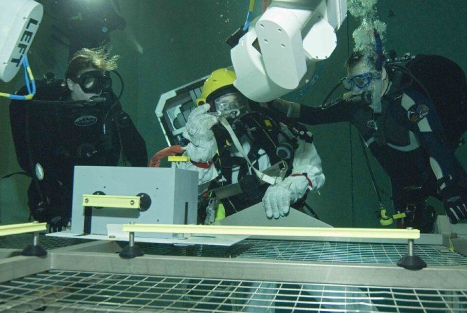Astronaut trener på jobb som skal utføres sammen med en robot under romvandring i en vanntank på jorda. Denne treningsversjonen av roboten heter Eurobot Wet Model. (Foto: ESA/H. Rub)