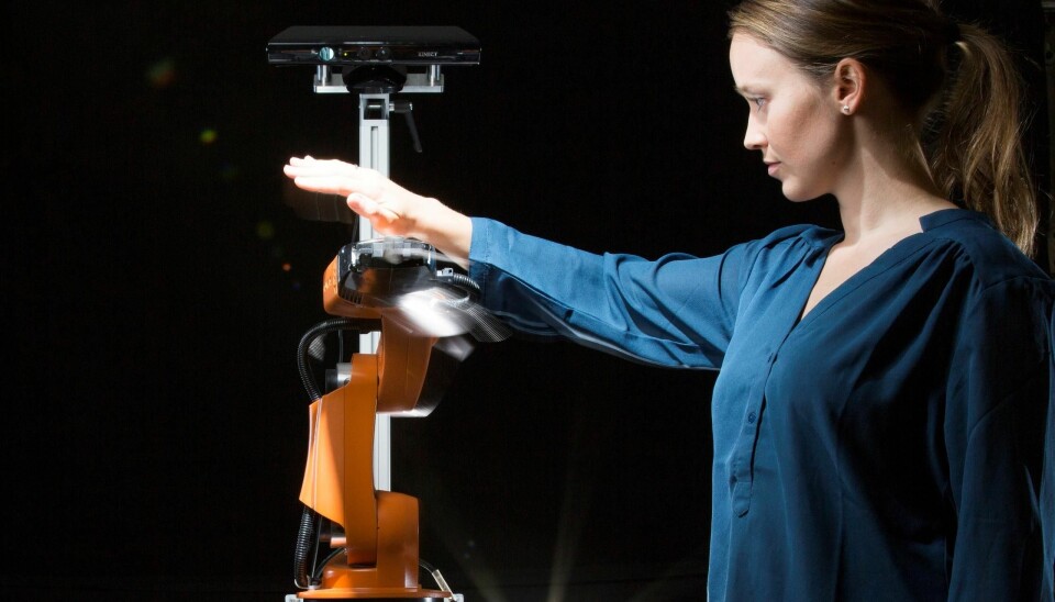 Researcher Marianne Bakken attempting to get close and personal with an orange robot arm – moving in all directions to try to get the robot to collide with her. But it manages to avoid her every time. (Photo: Werner Juvik)