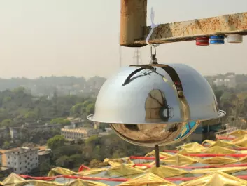 The image shows air samplers in the city of Chittagong in Bangladesh. The large "metal dome" collects air samples for analysis of environmental pollutants, while the three small cylinders measure nitrogen dioxide (blue), sulfur dioxide (red) and ozone (white). (Photo: Scott Randall, NILU)