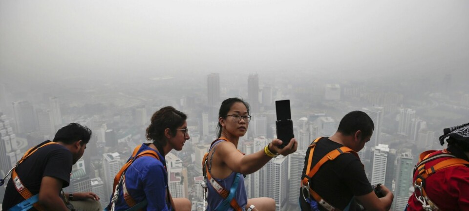 En kvinnelig turist tar en selfie på toppen av et høyt bygg i Kuala Lumpur i Malaysia i begynnelsen av oktober. Skogbranntåke ligger tykt over Kuala Lumpur, Singapore og andre steder i området. (Foto: Fazry Ismail/Epa)