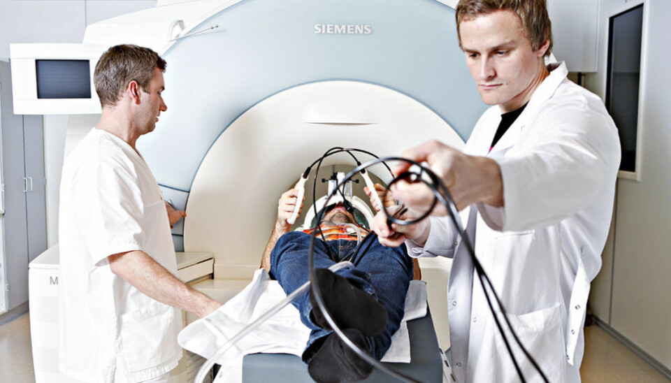 Chief Radiographer Bjarte Snekvik and Associate Professor Alexander Olsen illustrate how their study subjects perform the fMRI task (the person in the photo was not a study participant). Study participants used specially designed response buttons (as shown) and could view the task through video goggles. (Photo: Geir Mogen, NTNU)