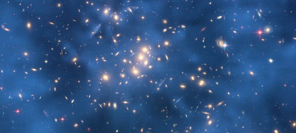 Mørk materie er usynlig, men kan registreres gjennom såkalt gravitasjonslinsing. Her ser vi den mørke materien som en blå ring rundt galaksen CL0024+17. (Foto: Jee og Ford mfl, NASA/ESA)