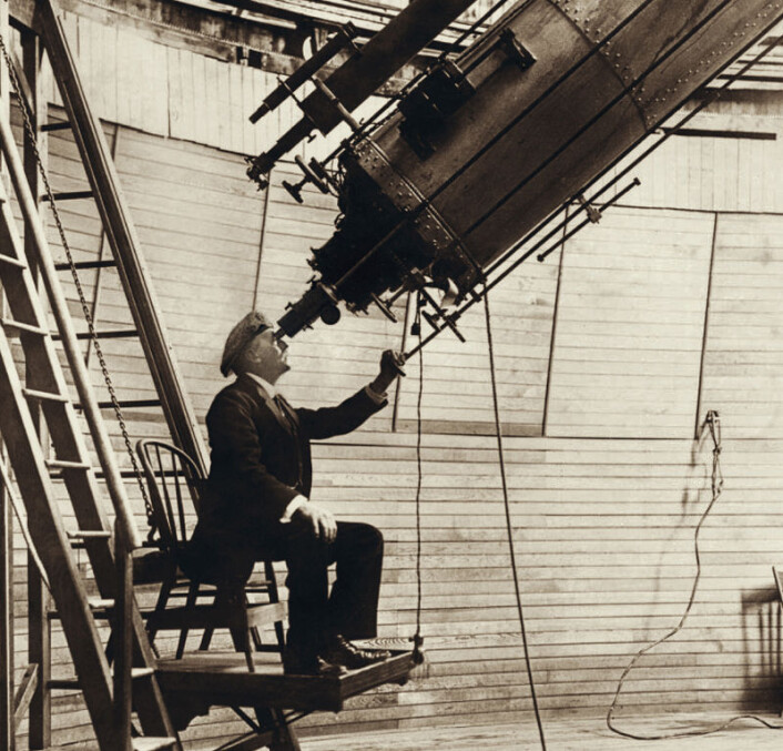 Percival Lowell observerer planeten Venus i 1914 gjennom 24-tommers linseteleskopet ved observatoriet han grunnla i Flagstaff, Arizona. Lowell var intenst opptatt av å finne den mystiske kjempeplaneten Planet X utenfor Neptuns bane, ikke minst for å gjenopprette kollegers faglige tillit til ham. På begynnelsen av 1900-tallet hadde han nemlig lansert idéen om at de imaginære kanalene på planeten Mars var laget av intelligente skapninger. (Foto: Ukjent/Public domain) Percival Lowell observerer planeten Venus i 1914 gjennom 24-tommers linseteleskopet ved observatoriet han grunnla i Flagstaff, Arizona. Lowell var intenst opptatt av å finne den mystiske kjempeplaneten Planet X utenfor Neptuns bane, ikke minst for å gjenopprette kollegers faglige tillit til ham. På begynnelsen av 1900-tallet hadde han nemlig lansert idéen om at de imaginære kanalene på planeten Mars var laget av intelligente skapninger. (Foto: Ukjent/Public domain)