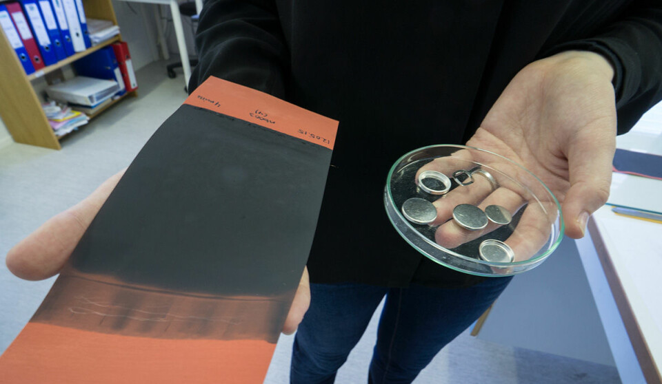 Til venstre holder Hanne Andersen et flak av silisium og karbon. Det skal skjæres opp i rundinger som passer inn i batterihylstrene hun holder i den andre hånden. (Foto: Arnfinn Christensen, forskning.no)