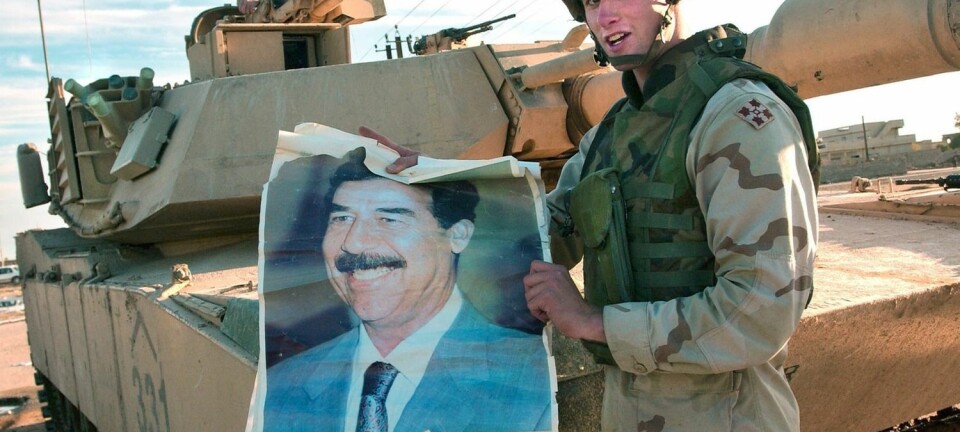 En amerikansk soldat fra 2003 viser frem en plakat av den avsatte irakiske presidenten Saddam Hussein. US Army Research Lab påpeker at den nye, matematiske logikken, som er utviklet ved Universitetet i Oslo, kan bedre det amerikanske etterretningsarbeidet. (Foto: Stefan Zaklin, EPA)