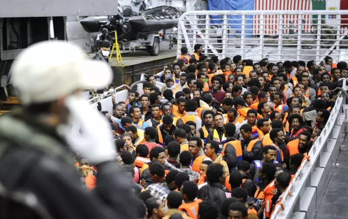 Flyktninger fra afrikanske land sør for Sahara står på et av den italienske marinens skip etter å ha blitt reddet i internasjonalt farvann mellom Italia og Libya 14. mai i fjor. Skipet San Giorgio er et av fem skip som er involvert i lete- og redningsoperasjonene som kalles Mare Nostrum – Vårt hav. (Foto: Reuters)