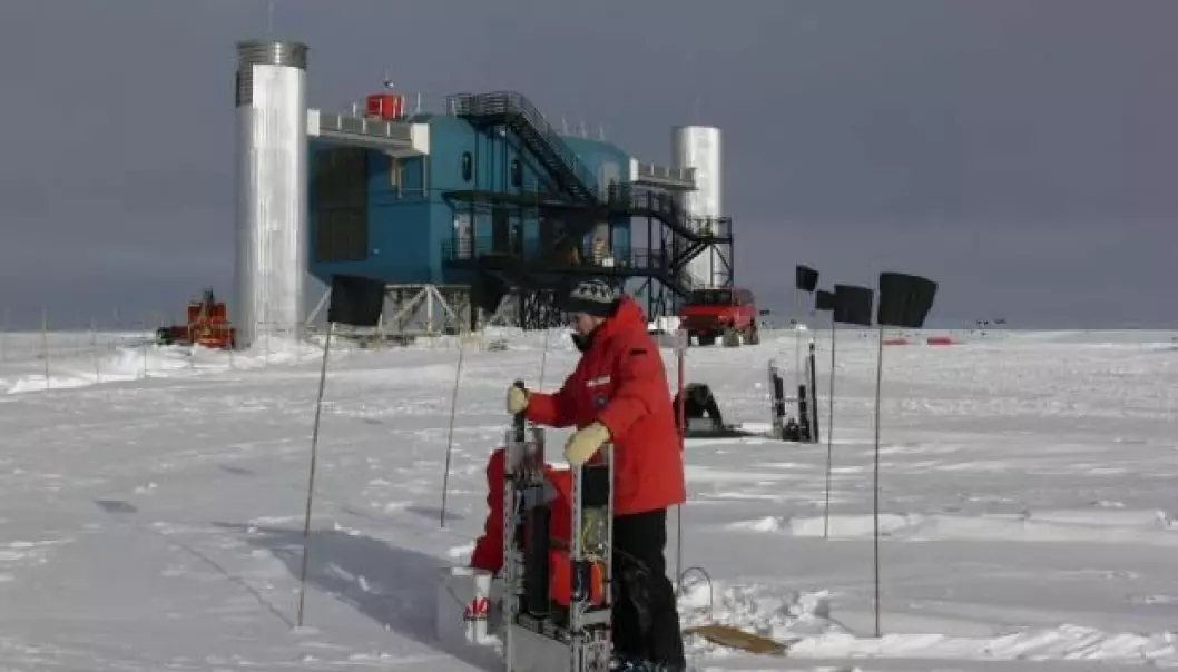 Jason Koskinen fra Københavns Universitet foran den kjempestore IceCube-detektoren på Sydpolen. Den leter etter nøytrinoer med instrumenter dypt nede i isen. Alle data fra instrumentene kommer opp gjennom de to «tårnene» og inn til et datasenter.  (Foto: T. Waldemaier)
