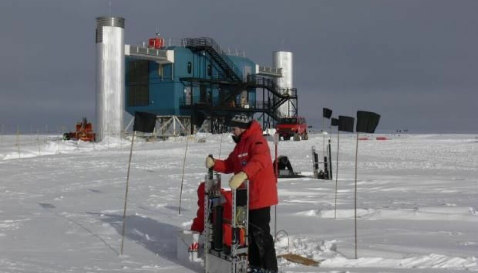 Jason Koskinen fra Københavns Universitet foran den kjempestore IceCube-detektoren på Sydpolen. Den leter etter nøytrinoer med instrumenter dypt nede i isen. Alle data fra instrumentene kommer opp gjennom de to «tårnene» og inn til et datasenter.  (Foto: T. Waldemaier)