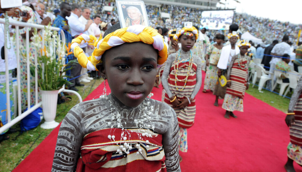 Unge jenter i Benin hilste paven velkommen med bilder av ham i hodebåndene da den daværende paven kom på besøk til det vestafrikanske landet i 2011. Benin regnes som opprinnelsessted til tradisjonell voodoo-religion, men får i likhet med mange andre afrikanske land stadig flere kristne innbyggere. Kristendommen her blir på sin side påvirket av spirituelle uttrykksformer. (Foto: AFP/NTB) Unge jenter i Benin hilste paven velkommen med bilder av ham i hodebåndene da den daværende paven kom på besøk til det vestafrikanske landet i 2011. Benin regnes som opprinnelsessted til tradisjonell voodoo-religion, men får i likhet med mange andre afrikanske land stadig flere kristne innbyggere. Kristendommen her blir på sin side påvirket av spirituelle uttrykksformer. (Foto: AFP/NTB)