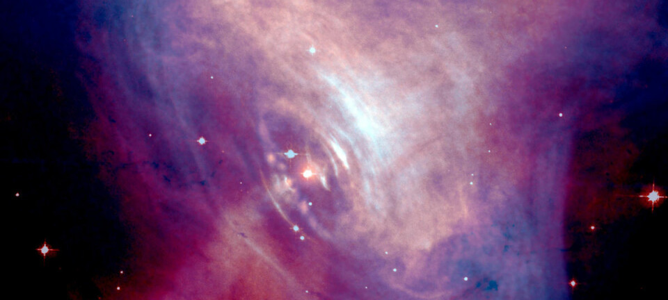 Radioastronomer vil bruke blinkende stjerner, pulsarer, til å lete etter de mystiske tyngdekraftbølgene. Einstein forutså dem, men ennå har ingen kunnet påvise dem direkte. Dette er en pulsar i Krabbetåken, omgitt av en glødende gassky. Bildet er sammensatt av fotografier i synlig lys (rødt) og røntgenstråler (blått) tatt med romteleskopet Hubble. (Foto: Synlig lys: NASA/HST/ASU/J. Hester et al. Røntgen: NASA/CXC/ASU/J. Hester et al.)