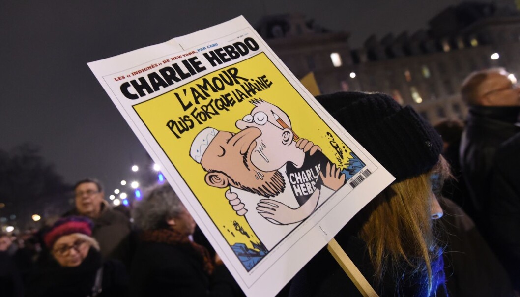 En kvinne holder en plakat av en Charlie Hebdo-forside med teksten Kjærlighet sterkere enn hat. Bildet ble tatt under markeringen på Place de la Republique i Paris 7. januar 2015, etter angrepet på redaksjonen til satiremagasinet Charlie Hebdo der 12 mennesker ble drept. (Foto: Scanpix, Dominique Faget) En kvinne holder en plakat av en Charlie Hebdo-forside med teksten Kjærlighet sterkere enn hat. Bildet ble tatt under markeringen på Place de la Republique i Paris 7. januar 2015, etter angrepet på redaksjonen til satiremagasinet Charlie Hebdo der 12 mennesker ble drept. (Foto: Scanpix, Dominique Faget)
