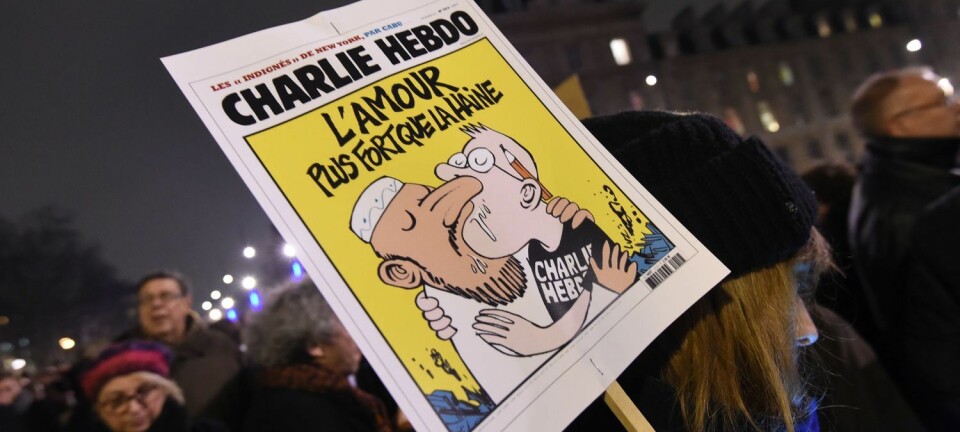 En kvinne holder en plakat av en Charlie Hebdo-forside med teksten Kjærlighet sterkere enn hat. Bildet ble tatt under markeringen på Place de la Republique i Paris 7. januar 2015, etter angrepet på redaksjonen til satiremagasinet Charlie Hebdo der 12 mennesker ble drept.   (Foto: Scanpix, Dominique Faget)