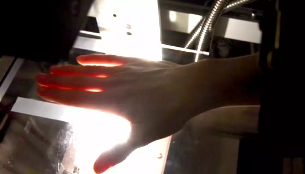 Hvitt lys går gjennom fingrene, og fine fargenyanser registreres av et hyperspektralt kamera. Dataanalyse av hvordan lyset endres gjennom hånden, kan gjøre det mulig å oppdage leddbetennelse raskt og tidlig. (Foto: Lise Randeberg)