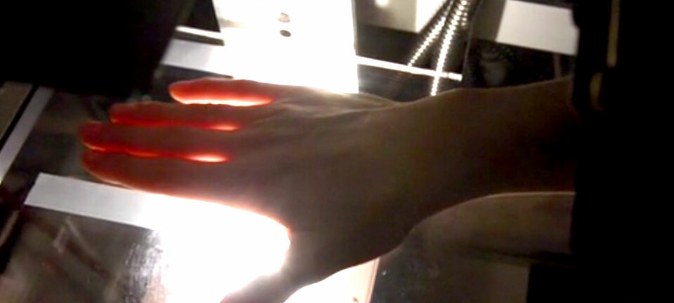 Hvitt lys går gjennom fingrene, og fine fargenyanser registreres av et hyperspektralt kamera. Dataanalyse av hvordan lyset endres gjennom hånden, kan gjøre det mulig å oppdage leddbetennelse raskt og tidlig. (Foto: Lise Randeberg)