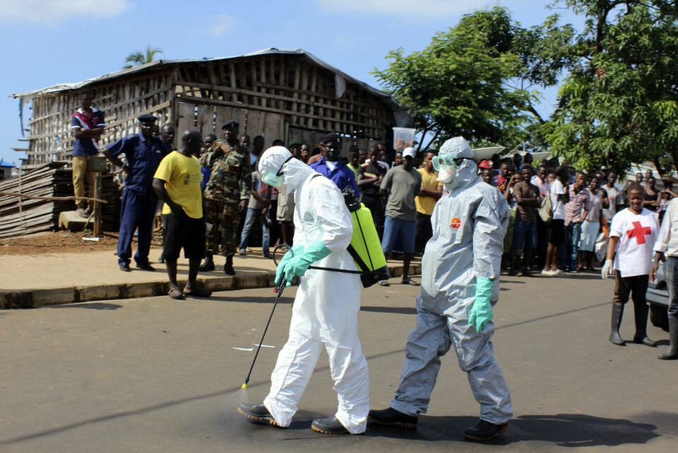 Helsearbeidere desinfiserer seg selv etter å ha hentet en død kvinne i Freetown i SierraLeone. (Foto: Josephus Olu-Mammah, Reuters)