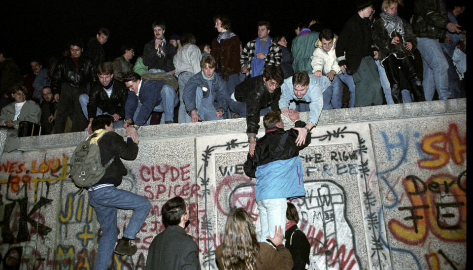 Tusenvis av mennesker krabbet opp på muren ved Brandenburger Tor i Vest-Berlin fredag 9. november 1989.  (Foto: Scanpix, Jørn H. Moen)