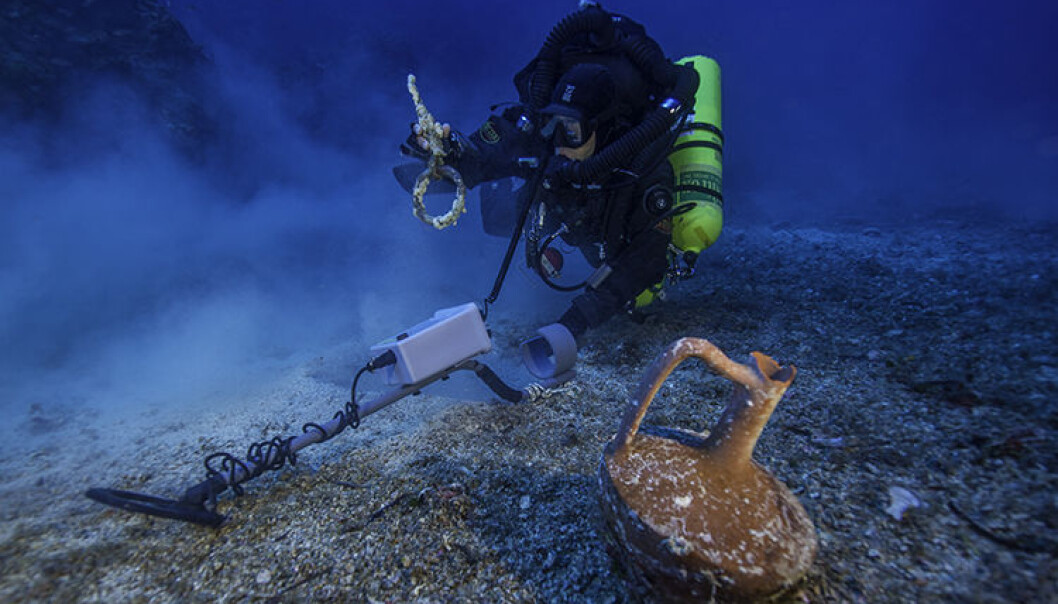 bildet viser arkeologene i arbeid med en metalldetektor. Den uskadde keramikkrukken sees i forgrunnen. (Foto: Brett Seymour, Copyright: Return to Antikythera 2014) bildet viser arkeologene i arbeid med en metalldetektor. Den uskadde keramikkrukken sees i forgrunnen. (Foto: Brett Seymour, Copyright: Return to Antikythera 2014)
