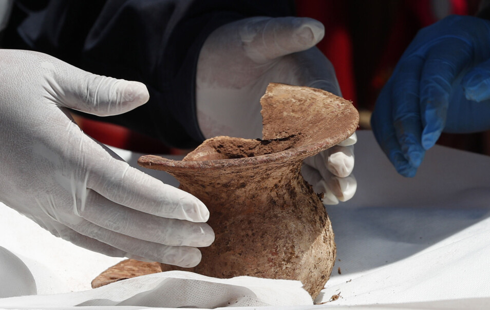 En arkeolog viser hva de har funnet ved Kalasasaya-templet. De tror denne gjenstanden, som har en vaselignende form, ble gitt under ofring i forbindelse med en begravelse av en person av høy rang. (Foto: AP, NTB scanpix)