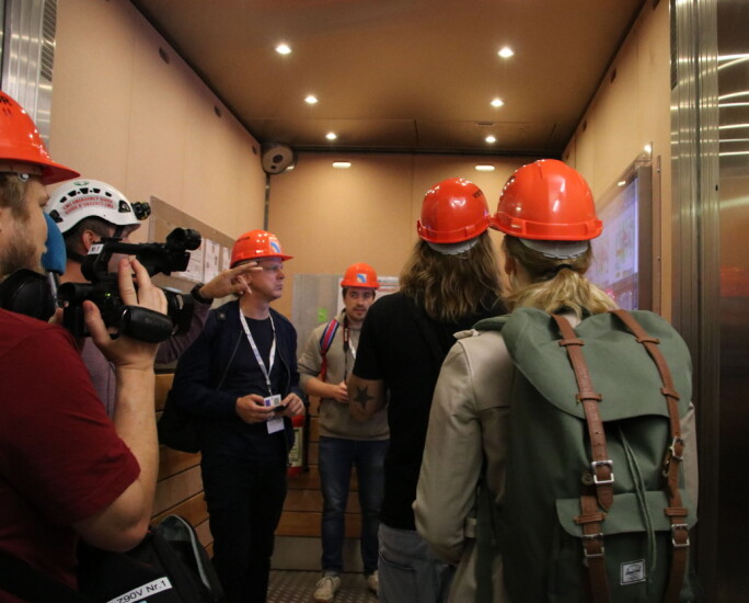 Journalistene går, uten å nøle, inn i heisen som skal frakte dem 100 meter under bakken. (Foto: Lasse Biørnstad)