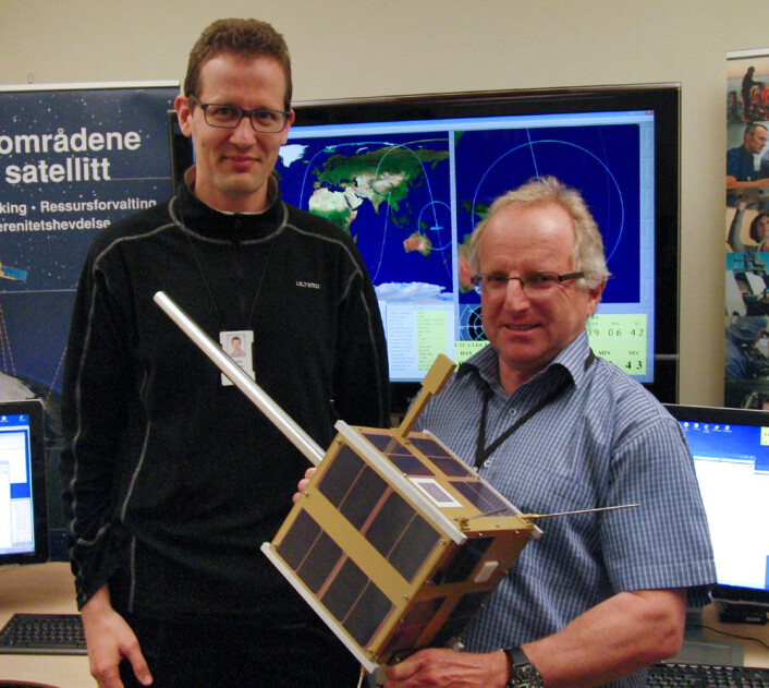 Øystein Helleren (t.v.) og Richard B. Olsen med fullskalamodell av AISSat-1 i kontrollrommet på Forsvarets Forskningsinstitutt der signalene fra satellitten overvåkes. Satellitten måler 20x20x20 cm, og stangen som stikker ut er antennen som tar imot signaler fra skip. (Foto: Arnfinn Christensen, forskning.no) Øystein Helleren (t.v.) og Richard B. Olsen med fullskalamodell av AISSat-1 i kontrollrommet på Forsvarets Forskningsinstitutt der signalene fra satellitten overvåkes. Satellitten måler 20x20x20 cm, og stangen som stikker ut er antennen som tar imot signaler fra skip. (Foto: Arnfinn Christensen, forskning.no)